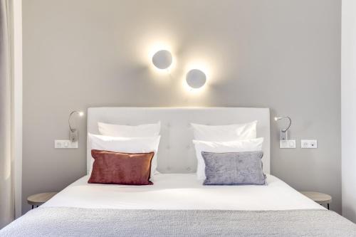un letto bianco con due cuscini sopra di Hotel Courseine a Courbevoie