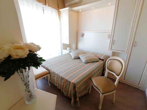 a small bedroom with a bed and a vase of flowers at Hotel Nordic in Bellaria-Igea Marina