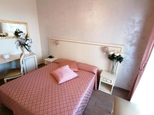 a small bedroom with a pink bed and two tables at Hotel Nordic in Bellaria-Igea Marina