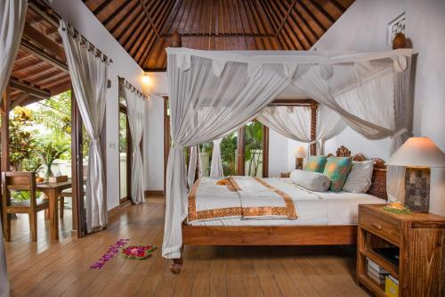 een slaapkamer met een hemelbed en een tafel bij Secluded Jungle Villa in Ubud