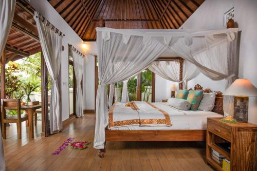 a bedroom with a canopy bed and a table at Secluded Jungle Villa in Ubud
