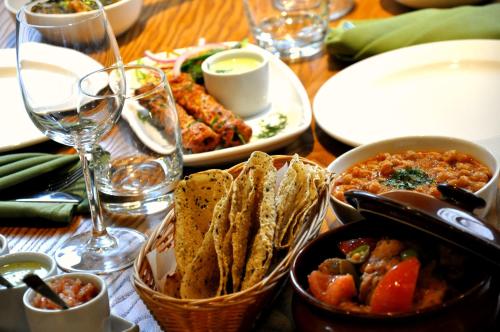 einen Tisch mit Teller mit Speisen und Gläsern Wein in der Unterkunft Hotel Serena Palace in Multan