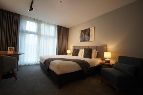 una habitación de hotel con una cama grande y una silla en City Edge South Melbourne Apartment Hotel, en Melbourne