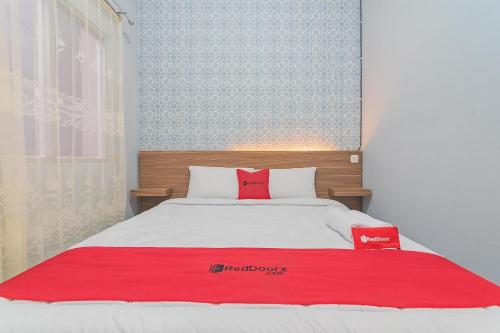 a bedroom with a bed with a red blanket on it at RedDoorz near Alun-Alun Garut in Garut