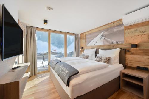 a bedroom with a large bed and a television at Mountain Hotel Luis in Kaprun