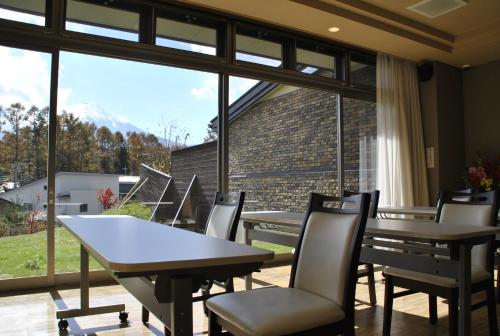 a dining room with tables and chairs and a large window at The Gran Resort Princess Fujikawaguchiko in Fujikawaguchiko