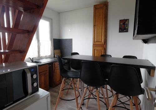 une cuisine avec un comptoir noir et des tabourets de bar noirs dans l'établissement Sea Wind and Sun, à Wimereux