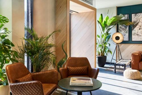 a lobby with chairs and a table and plants at Hotel Indigo Antwerp City Centre by IHG in Antwerp