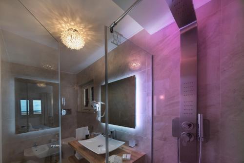 a bathroom with a shower, sink, and mirror at Artemide Hotel in San Vito lo Capo