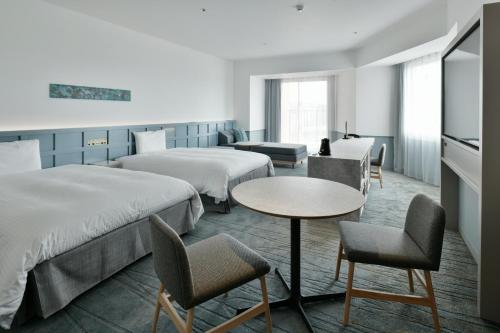 北谷町的住宿－Lequ Okinawa Chatan Spa ＆ Resort，酒店客房带两张床和一张桌子以及椅子。