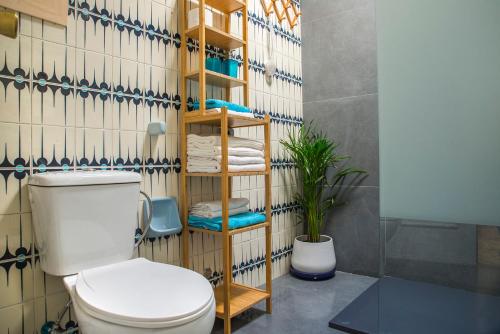 a bathroom with a toilet and a shelf with towels at Casa Venice in Chiclana de la Frontera