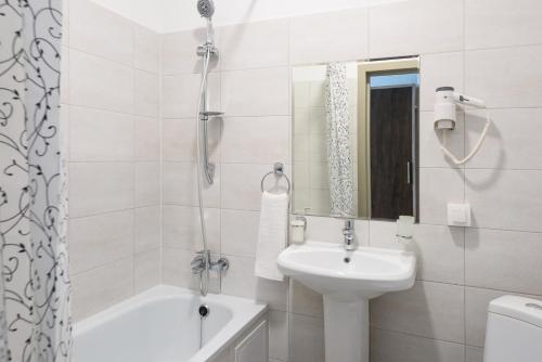 biała łazienka z umywalką i wanną w obiekcie NCityHotel w mieście Astana