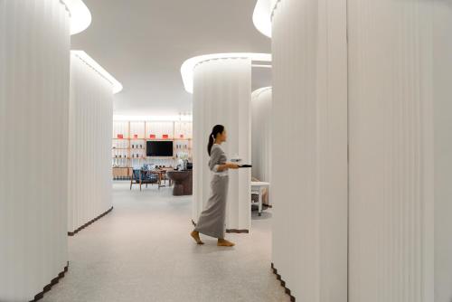 a woman walking through a hallway with white walls at Melia Koh Samui in Choeng Mon Beach