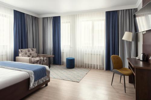 a hotel room with a bed and a chair and a desk at NCityHotel in Astana