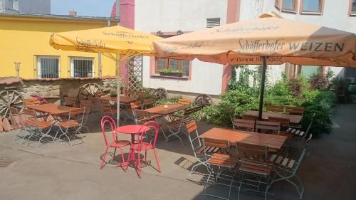 an outdoor patio with tables and chairs and umbrellas at HotelDeutschesHaus Leinefelde in Leinefelde