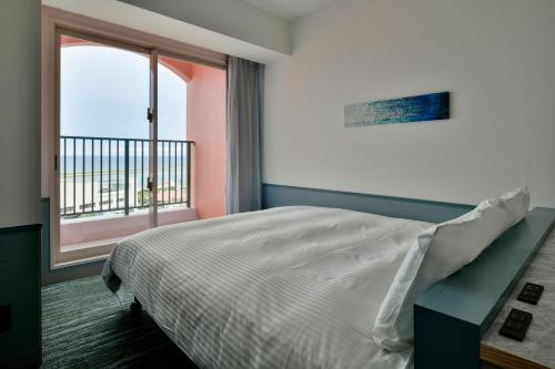 a bedroom with a bed and a large window at Lequ Okinawa Chatan Spa ＆ Resort in Chatan
