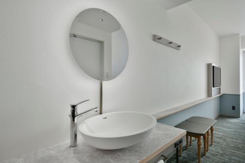 a bathroom with a white sink and a mirror at Lequ Okinawa Chatan Spa ＆ Resort in Chatan