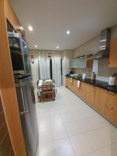 a kitchen with a stainless steel refrigerator and a table at Apartamento T3 Ponta Delgada in Ponta Delgada