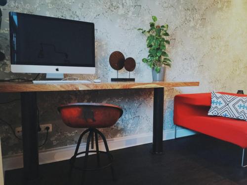 a desk with a computer monitor and a red chair at 36 Phô Cô Hotel & Suites in Weimar
