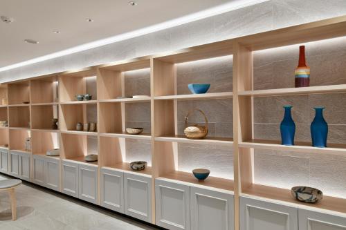a wall of shelves with vases and bowls at Lequ Okinawa Chatan Spa ＆ Resort in Chatan