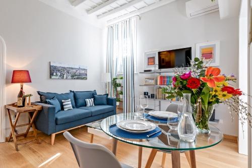 a living room with a glass table and a blue couch at Rome as you feel - Grotta Pinta apartments in Rome