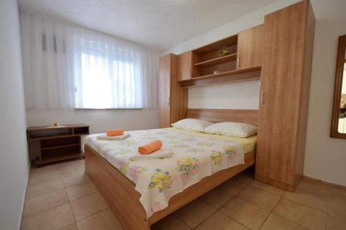 sypialnia z łóżkiem z drewnianym zagłówkiem w obiekcie Apartments Buturajac w Krku