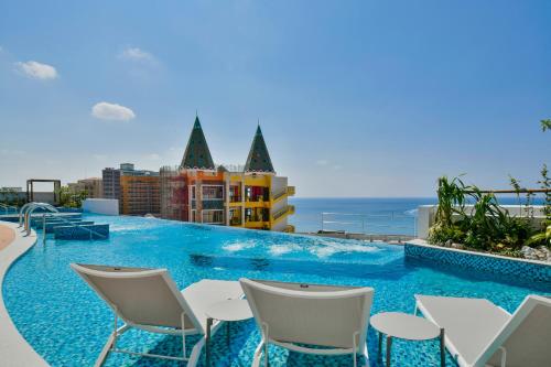 a swimming pool with chairs and the ocean in the background at Lequ Okinawa Chatan Spa ＆ Resort in Chatan