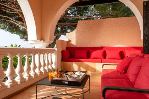 a living room with a red couch and a table at Hôtel Les Mouettes - Teritoria in Ajaccio
