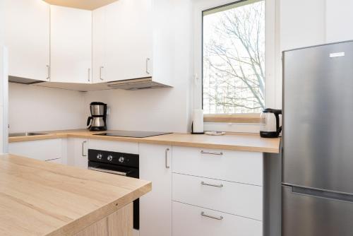 La cuisine est équipée de placards blancs et d'un réfrigérateur en acier inoxydable. dans l'établissement Apartment Nevada Gdańsk Przymorze by Renters, à Gdańsk