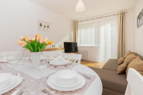 - un salon doté d'une table avec des assiettes et des fleurs dans l'établissement Apartment Nevada Gdańsk Przymorze by Renters, à Gdańsk