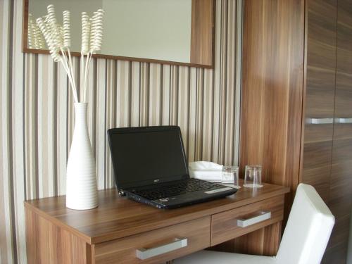 a laptop computer sitting on a wooden desk with a vase at Rezidence Fami Deluxe Design in Staré Splavy