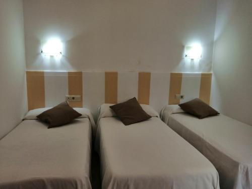 2 camas en una habitación con 2 luces en la pared en Hostal PILAS ALCARAYÓN, en Pilas