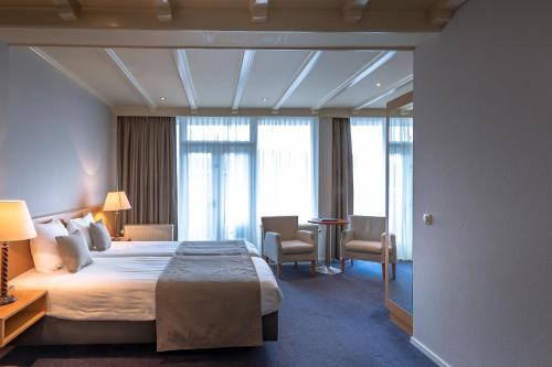 a hotel room with a large bed and windows at Hotel Restaurant De Zwaan in Raalte