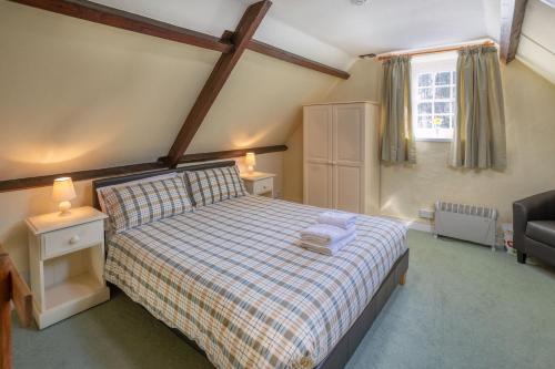 a bedroom with a bed and a chair and a window at La Bellieuse Cottages in St Martin Guernsey