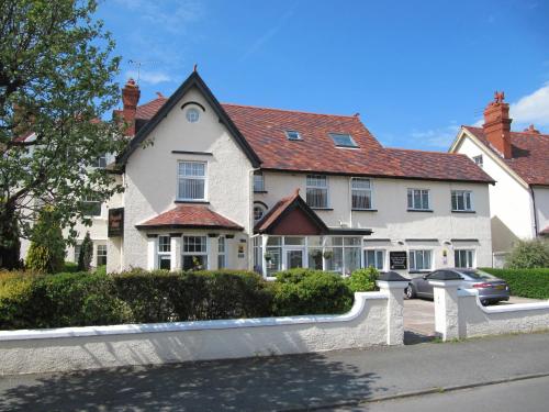 a white house with a car parked in front of it at Brigstock House in Llandudno