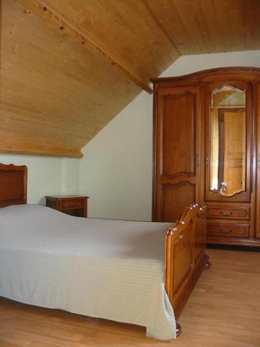 une chambre avec un lit et une armoire en bois dans l'établissement CHAMBRES D'HÔTES chez réjane, à Crasville