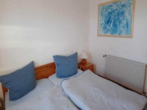 ein Schlafzimmer mit einem Bett und zwei blauen Kissen in der Unterkunft La Casa Ferienwohnung Kormoran in Steinberg