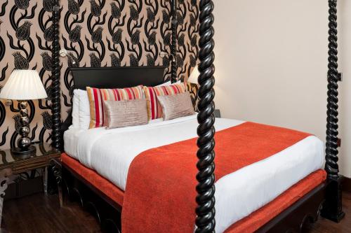 a bedroom with a four poster bed with a red blanket at Hotel Indigo London Tower Hill by IHG in London