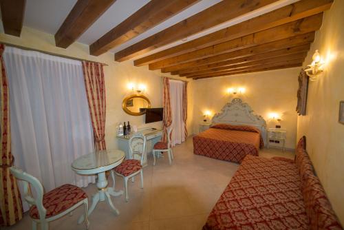 Locanda Ca' Zose في البندقية: غرفة فندقية بسرير وطاولة وكراسي