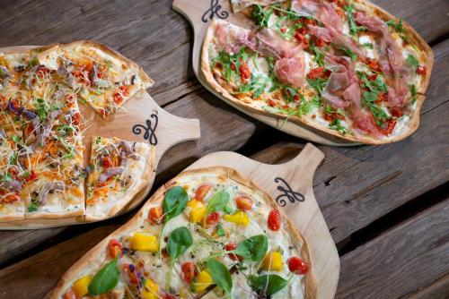three pizzas on wooden cutting boards on a table at mama thresl in Leogang