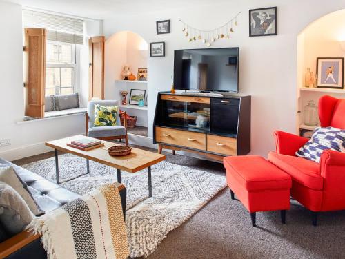 a living room with red chairs and a tv at 1 Pringles Yard in Alnwick