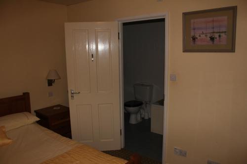 a bedroom with a bed and a door to a bathroom at The Haymaker Inn in Chard