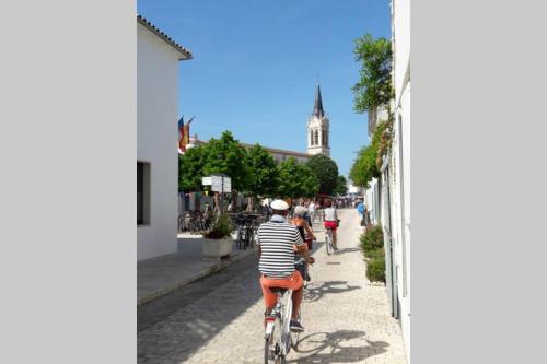 a group of people riding bikes down a street at La Virginie - Suite Parée'Ô in La Couarde-sur-Mer