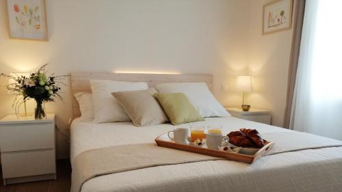 a bed with a tray of food and drinks on it at Gîtes Les Nogalies SPA PRIVATIF in Valojoulx