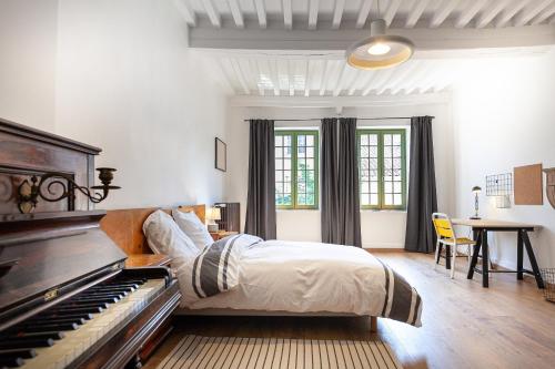 une chambre avec un lit et un piano dans l'établissement La maison des couturières, à Cluny