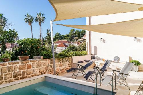 un patio con piscina, sillas y sombrilla en Apartments Villa Agava en Cavtat