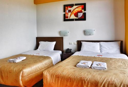 Dos camas en una habitación de hotel con toallas. en Pumas Cusco Hotel, en Cusco