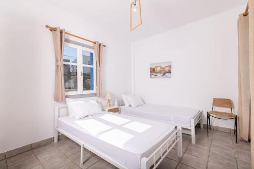 a white room with two beds and a window at VILLA KOSTA in Naousa-Paros in Naousa