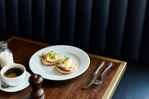 a table with a plate of food and a cup of coffee at Hotel Indigo London - 1 Leicester Square by IHG in London