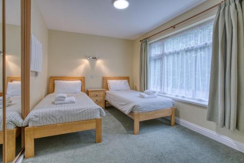 two twin beds in a room with a window at Del Mar Court in St Martin Guernsey